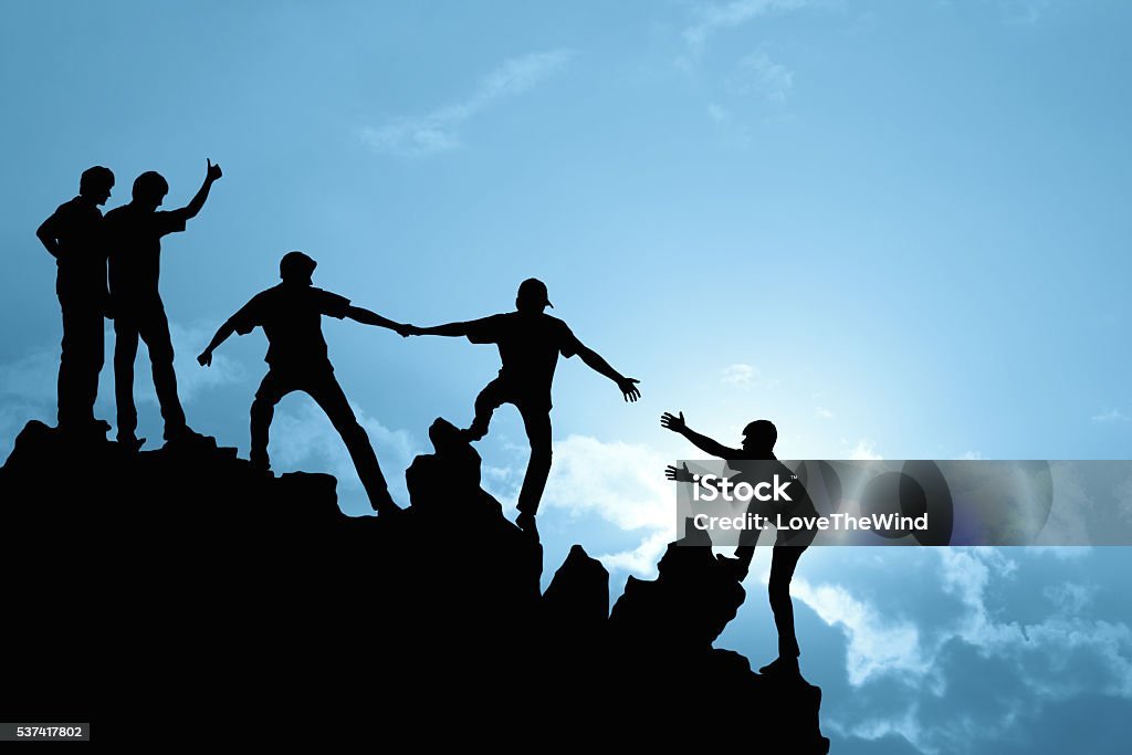 A group of people helping each other climb a mountain, symbolizing teamwork and support in fitness journeys. 